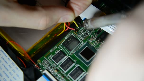Engenheiro eletrônico está soldando uma placa elétrica com processadores em um escritório escuro com telas de exibição — Vídeo de Stock