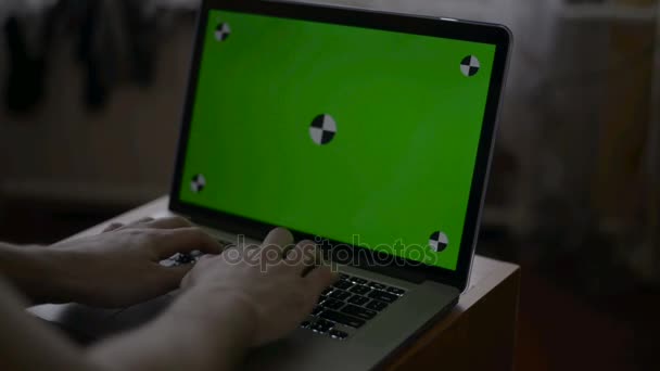 A man types on a laptop on his desk. Green screen for your custom screen content. — Stock Video