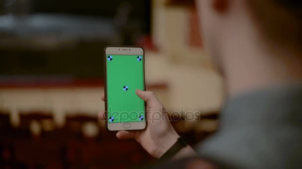 Закрыть человек держа слайд-сенсорный смартфон с зеленым экраном в театре Chroma Key — стоковое видео