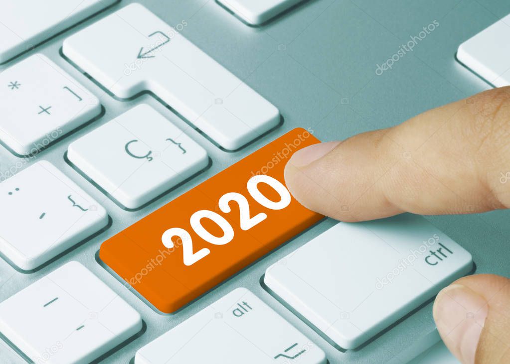 2020 - Inscription on Orange Keyboard Key. 2020 Written on Orange Key of Metallic Keyboard. Finger pressing key.  