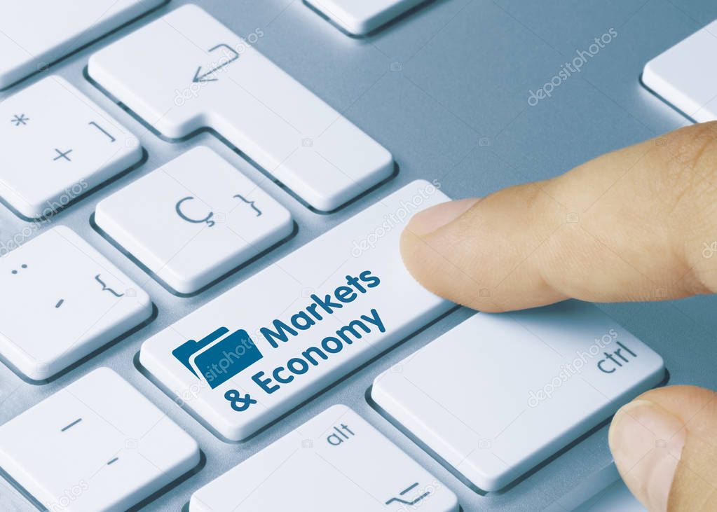 Markets & Economy - Inscription on White Keyboard Key. Markets & Economy Written on White Key of Metallic Keyboard. Finger pressing key.