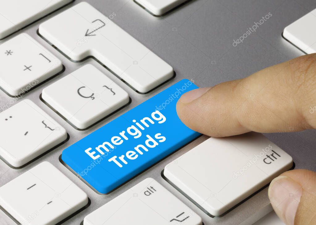 Emerging Trends Written on Blue Key of Metallic Keyboard. Finger pressing key