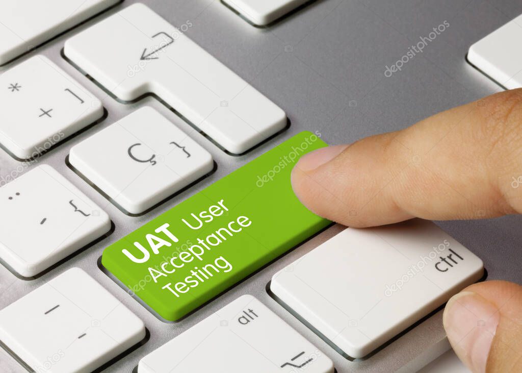 UAT User Acceptance Testing Written on Green Key of Metallic Keyboard. Finger pressing key.