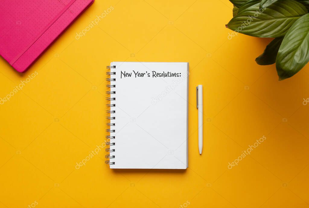 Stock photo of new year notebook with list of resolutions and objects on yellow background