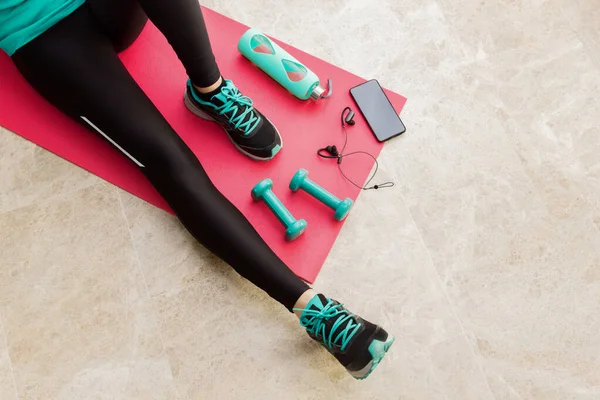 Stock photo of a young woman stretching after exercising at home in the living room — Stock Photo, Image