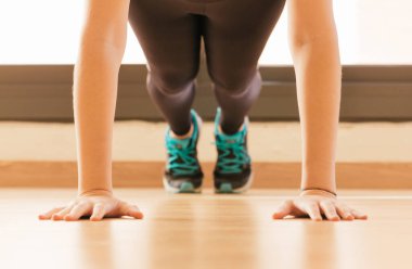 Evde şınav çeken genç bir kadının stok fotoğrafı.