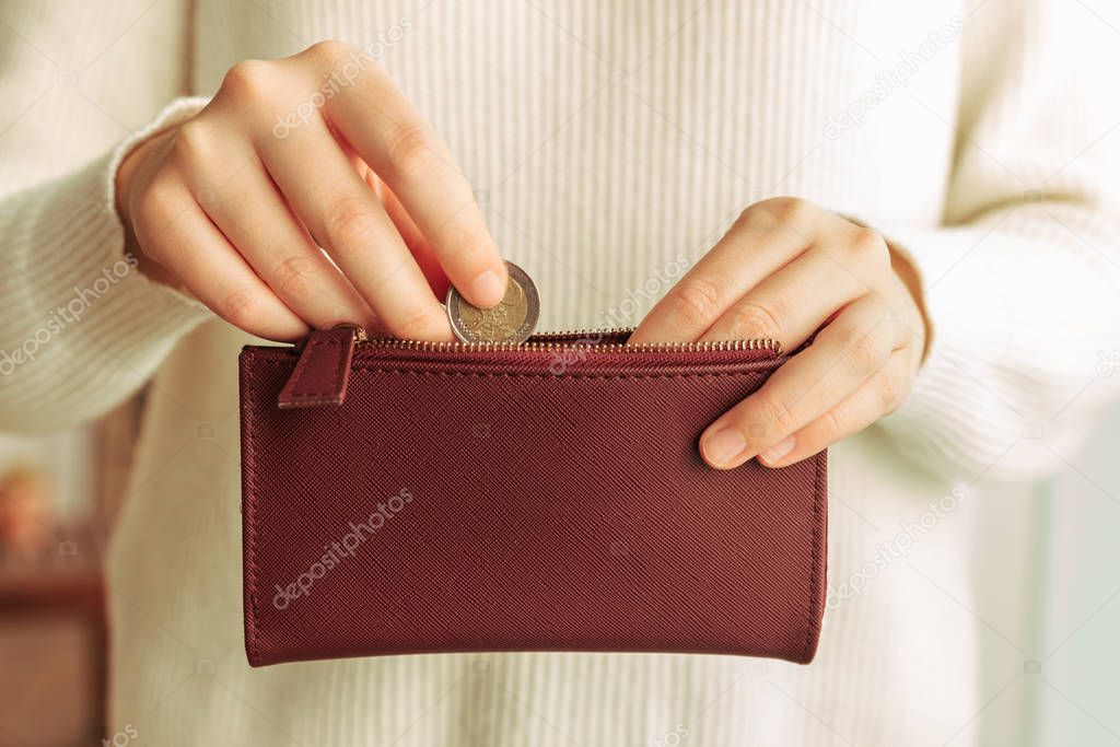 Stock photo of hands introducing a coin in a wallet