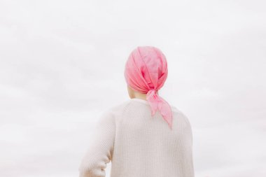 Kafasında pembe mendil olan bir kadının stok fotoğrafı. Kanser olmuş.