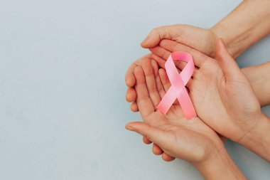 Kadınların elinde pembe bir kurdele ve solunda kopya alanı olan mavi bir arkaplan.
