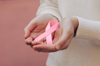 Kadının elinde pembe bir kurdele resmi var.