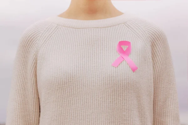Foto stock de uma mulher com uma fita rosa, símbolo de câncer, na camisola — Fotografia de Stock