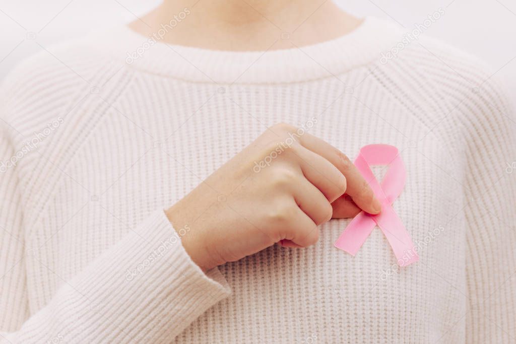 Stock photo of a woman with a pink ribbon, cancer symbol, in the sweater