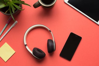 Bluetooth kulaklığın ve kırmızı arka planda akıllı telefonun stok fotoğrafı.