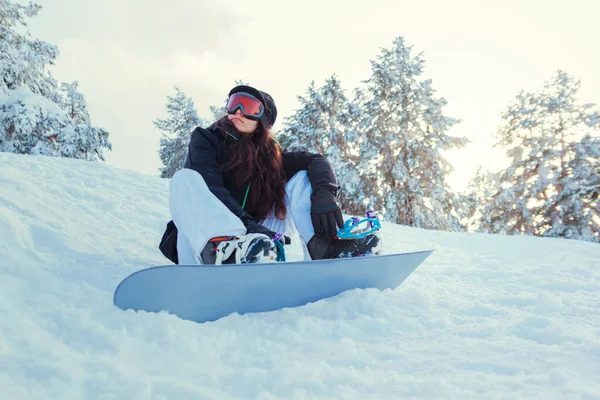 Foto d'archivio di una giovane donna snowboarder seduta sulla neve — Foto Stock