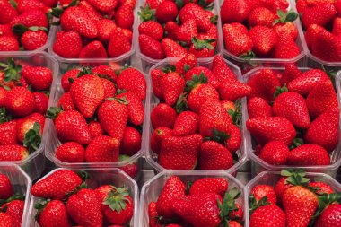 Marketteki lezzetli çileklerle dolu birkaç tepsinin resmi.