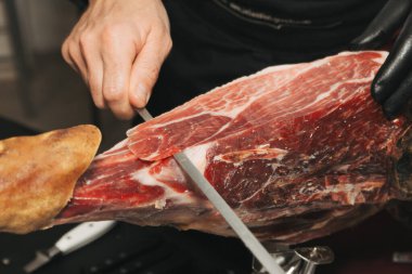 Usta bir İber jambonu kesicisinin el resmi. İber jambonu kesiyor.