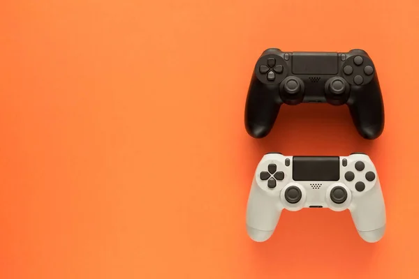 Foto Stock Dois Gamepads Fundo Laranja Espaço Cópia Esquerda — Fotografia de Stock