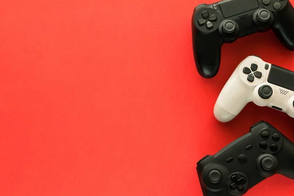 Foto Stock Três Gamepads Fundo Vermelho Espaço Cópia Lado Esquerdo — Fotografia de Stock