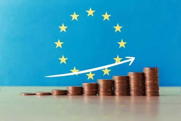 Stock photo of the concept of economic recovery and prosperity in Europe with an ascending staircase of coins and the flag in the background