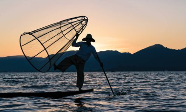 Inle Lake, Myanmar (Burma) - 30 Ocak 2018: Inle Gölü 'nde turistlere poz veren Burmalı balıkçı. Elindeki geleneksel balık ağları artık Intha halkı tarafından kullanılmıyor..