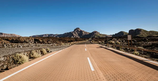 Empty road running through volcanic, rocky desert in Teide National Park, Tenerife, Spain.