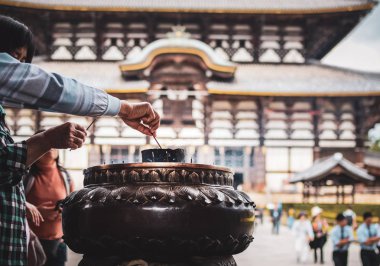 Nara, Japonya - 22 Ekim 2018: Seyyahlar Todai-ji tapınağında tütsü yakarken arka planda tapınağın kendisi de vardı..