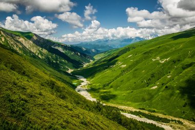 Büyüleyici Adishi Vadisi yaz manzarası Chkhutnieri Geçidi, Yukarı Svaneti, Georgia 'dan görülüyor. Kısmen bulutlu bir günde Kafkasya dağ sırasının canlı yeşil yamaçları.