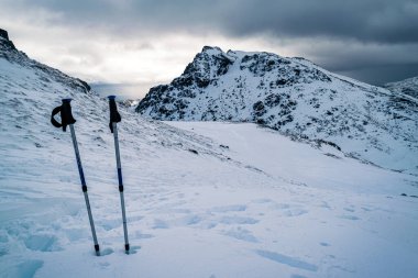 Ben Narnain, Arrochar, İskoçya - Mart 06, 2016: İki yürüyüş direği karda sıkışmış ve zeminde ayak izleri var..