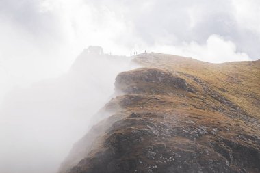 Cobbler 'ın tepesinde sisli engebeli uçurumları olan beş tepe yürüyüşçüsünün siluetleri. Dramatik İskoç manzarası.