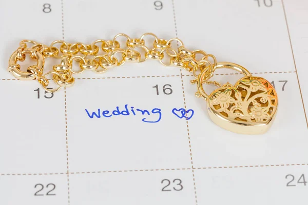 Слово свадьба на календаре и золотой браслет с сердцем — стоковое фото