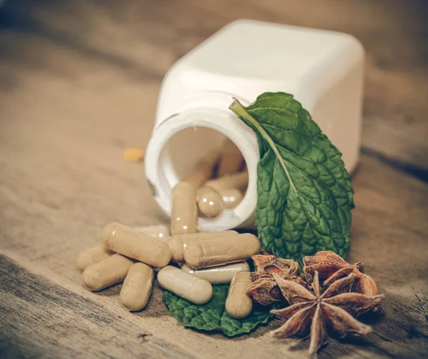 Mint leaf and Herb capsule spilling out of a bottle — Stock Photo, Image