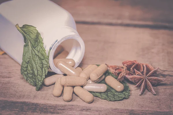 Mint leaf and Herb capsule spilling out of a bottle — Stock Photo, Image