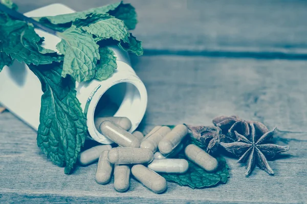 Folha de hortelã e cápsula Herb derramando de uma garrafa — Fotografia de Stock