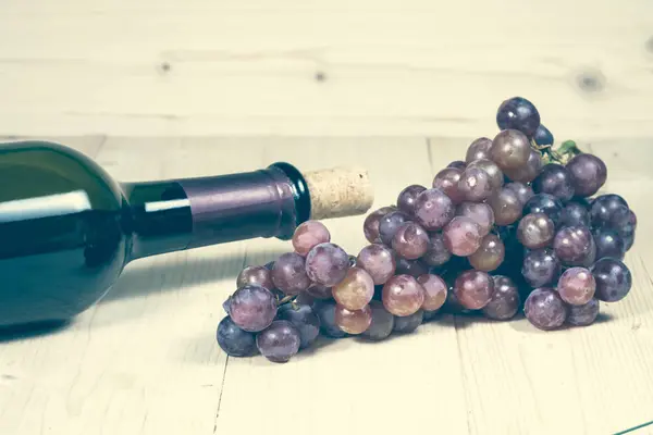 Grapes, and wine bottle on wood background — Stock Photo, Image