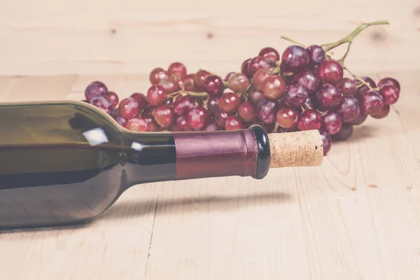 Grapes, and wine bottle on wood background — Stock Photo, Image