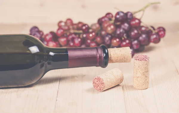Uvas y botella de vino sobre fondo de madera — Foto de Stock
