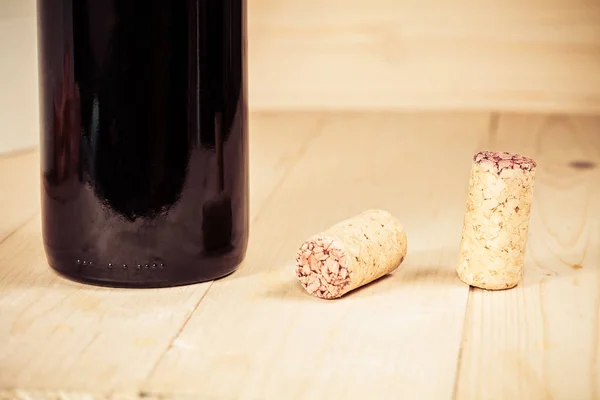 Garrafas de vinho tinto com rolhas na mesa de madeira — Fotografia de Stock