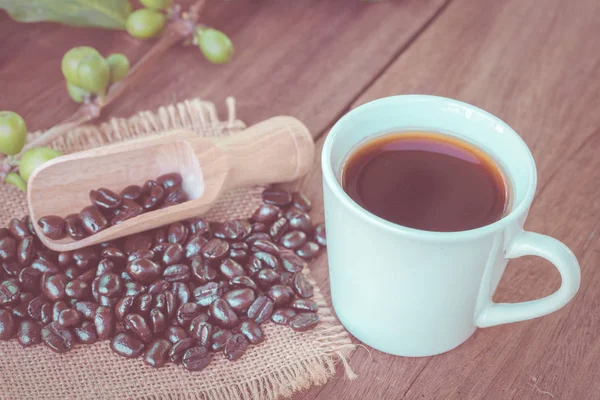 Fresh coffee beans on wood and coffee cup — Stock Photo, Image