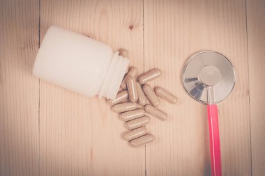 ot kapsül ve ahşap masa üzerinde stetoskop