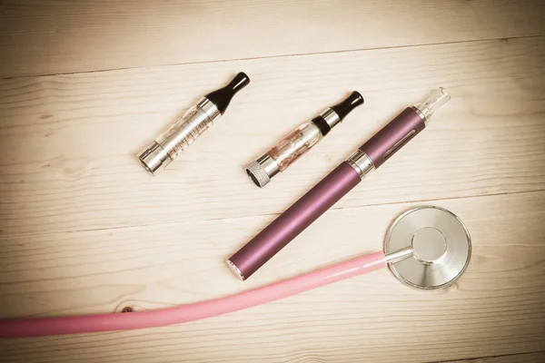 Stethoscope and e- cigarette on wood table — Stock Photo, Image