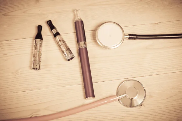 Stethoscope and e- cigarette on wood table — Stock Photo, Image