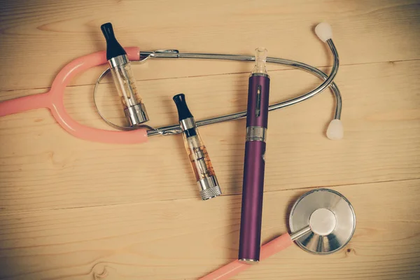 Stethoscope and e- cigarette on wood table — Stock Photo, Image