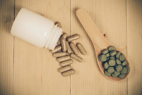Herb capsules spilling out of a bottle and herb pill — Stock Photo, Image