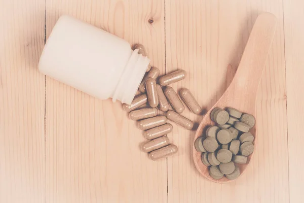 Herb capsules spilling out of a bottle and herb pill — Stock Photo, Image