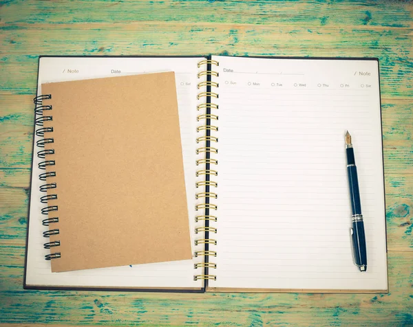 Üres fehér notebook és a toll a fa tábla — Stock Fotó