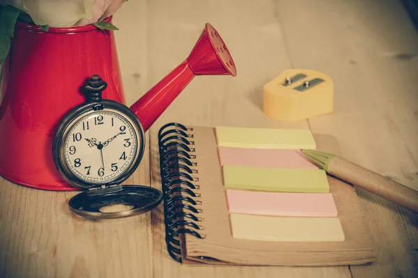 Zakhorloge met boek opmerking op houten achtergrond. — Stockfoto