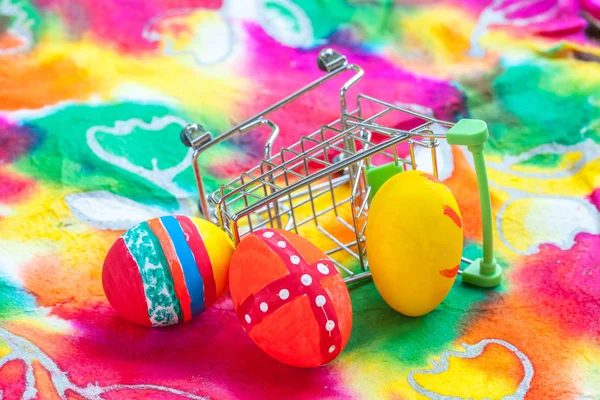 Velikonoční vajíčko v nákupním košíku na barevný papír — Stock fotografie