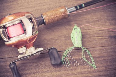Fishing tackle - Baitcasting Reel, hooks and lures on  wooden ba clipart