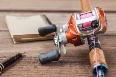 Mücadele - Baitcasting Reel, kitap ahşap arka plan üzerinde Balık tutma