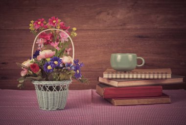 çiçek sepeti ve ahşap arka plan üzerinde eski kitap.